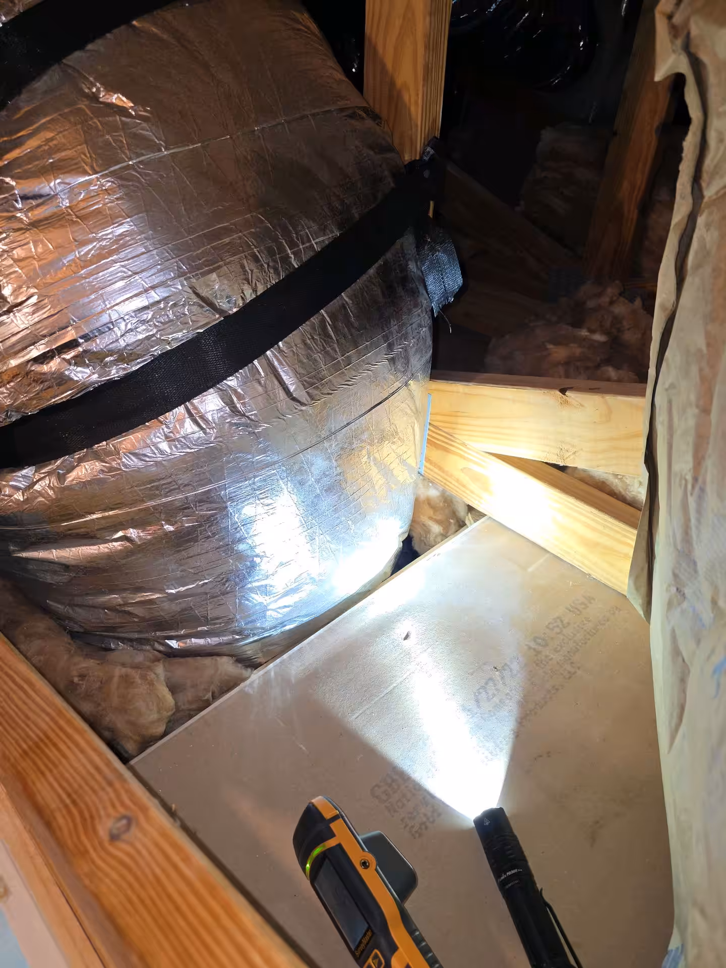 Visible moisture on the exterior of HVAC ductwork in an attic